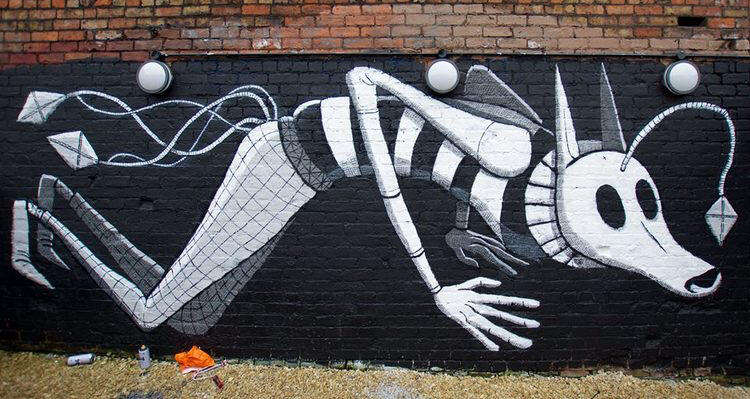 A black and white mural on a brick wall depicts a stylized, elongated figure with animalistic features and a striped outfit, suggesting movement and whimsy.